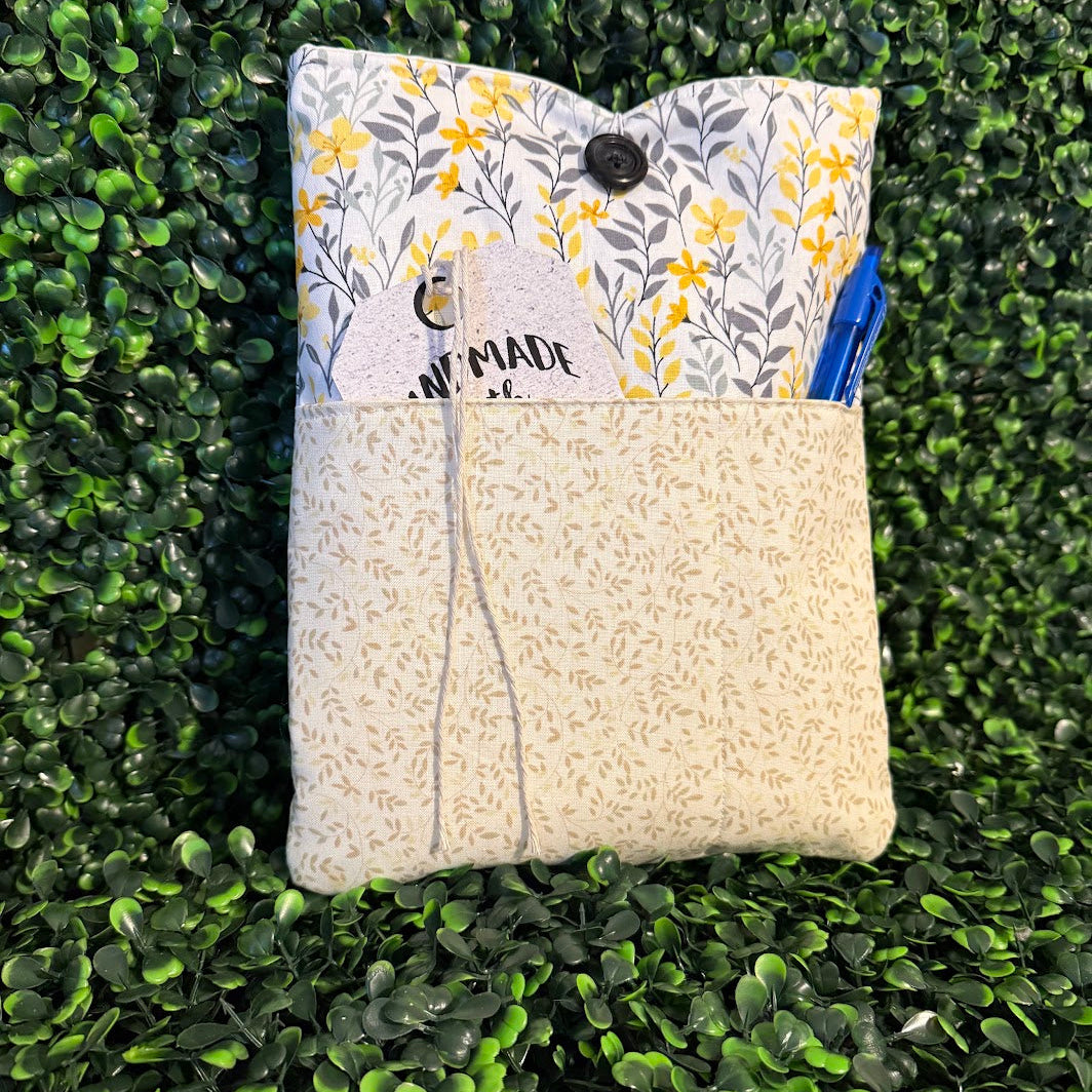 Floral-patterned pouch with a blue pen on a green grass background
